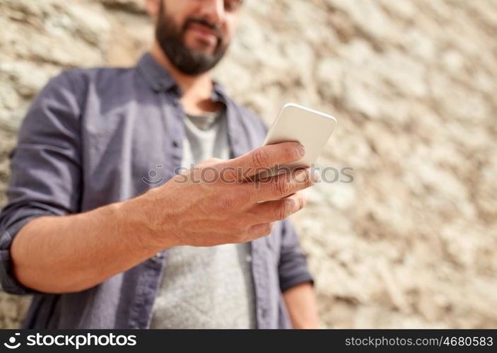 leisure, technology, communication and people concept - close up of man with smartphone at stone wall on street