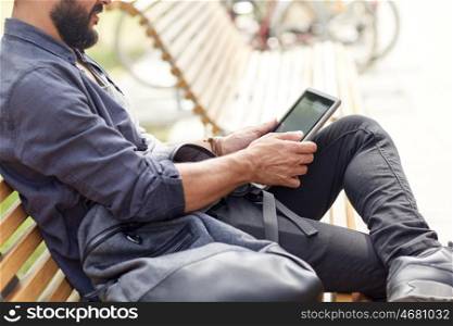 leisure, technology, communication and people concept - close up of man with tablet pc computer and bag sitting on city street bench