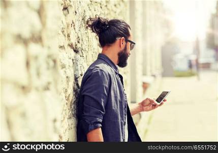 leisure, technology, communication and people concept - close up of man with smartphone at stone wall on street. close up of man with smartphone at stone wall. close up of man with smartphone at stone wall