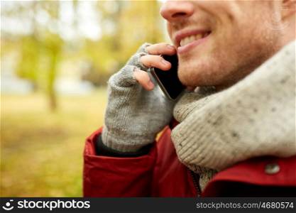 leisure, technology, communication and people concept - close up of smiling young man calling on smartphone in autumn