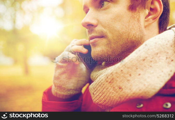 leisure, technology, communication and people concept - close up of young man calling on smartphone in autumn. close up of man with smartphone calling in autumn