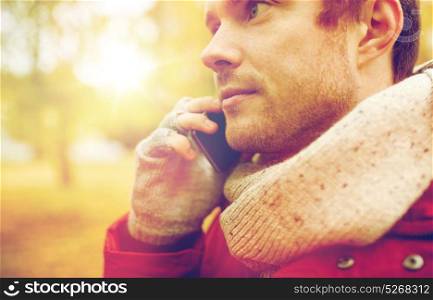 leisure, technology, communication and people concept - close up of young man calling on smartphone in autumn. close up of man with smartphone calling in autumn