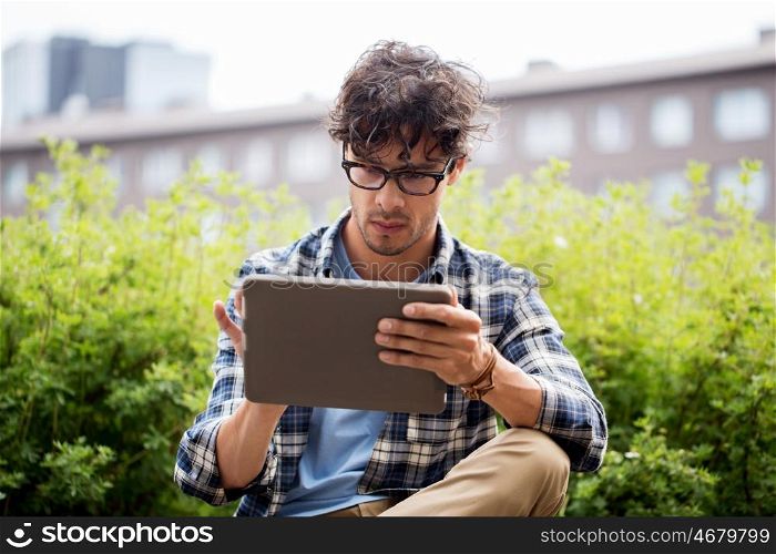 leisure, technology, communication and people concept - creative man in glasses with tablet pc computer in city