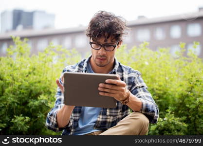 leisure, technology, communication and people concept - creative man in glasses with tablet pc computer in city