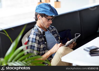 leisure, technology, communication and people concept - creative man with tablet pc computer and earphones listening to music at cafe table