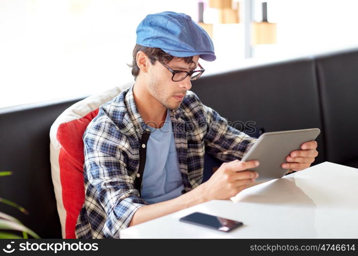 leisure, technology, communication and people concept - creative man with tablet pc computer sitting at cafe table