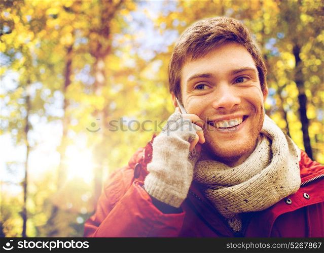 leisure, technology, communication and people concept - happy smiling young man calling on smartphone at autumn park. man with smartphone calling on city street