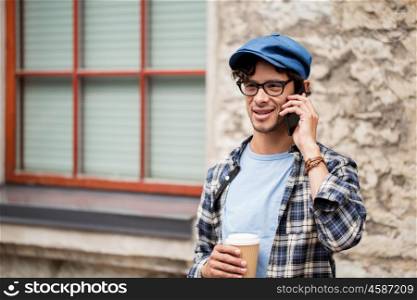 leisure, technology, communication and people concept - hipster man in eyeglasses calling on smartphone and drinking coffee on street