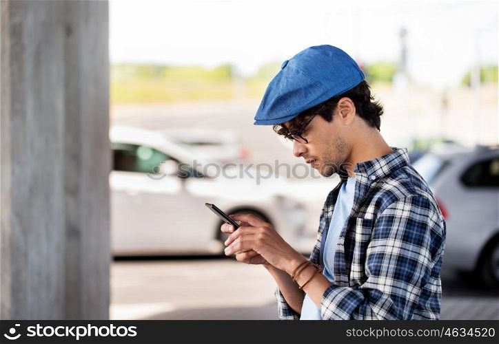 leisure, technology, communication and people concept - hipster man texting message on smartphone on city street