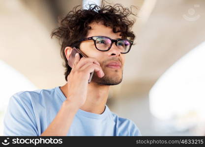 leisure, technology, communication and people concept - man in eyeglasses calling on smartphone on street