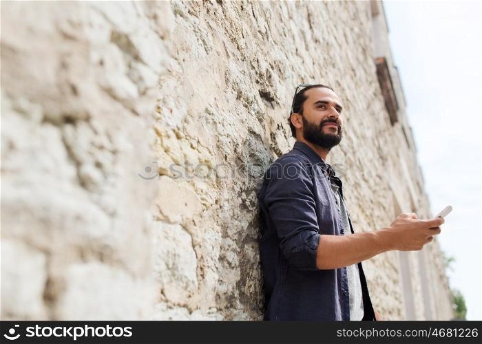 leisure, technology, communication and people concept - man with smartphone at stone wall