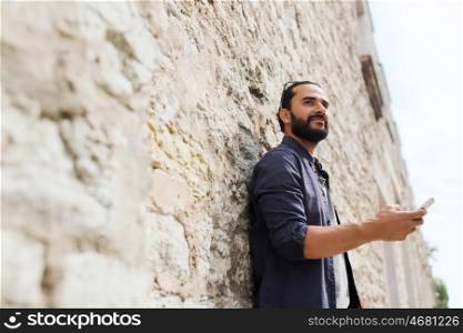 leisure, technology, communication and people concept - man with smartphone at stone wall