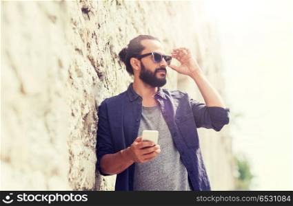 leisure, technology, communication and people concept - man with smartphone at stone wall. man with smartphone at stone wall. man with smartphone at stone wall