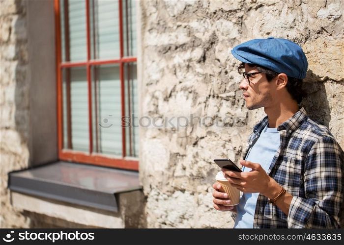 leisure, technology, communication and people concept - man with smartphone drinking coffee from disposable paper cup and texting message on city street