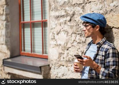 leisure, technology, communication and people concept - man with smartphone drinking coffee from disposable paper cup and texting message on city street