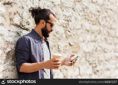 leisure, technology, communication and people concept - man with smartphone drinking coffee from disposable paper cup on city street