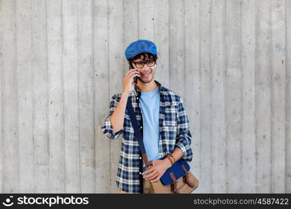 leisure, technology, communication and people concept - smiling hipster man with shoulder bag calling on smartphone at street wall