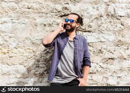leisure, technology, communication and people concept - smiling man calling on smartphone on street at stone wall