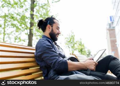 leisure, technology, communication, travel and people concept - man with tablet pc computer and bag sitting on city street bench
