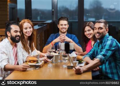 leisure, technology, friendship, people and holidays concept - happy friends having dinner and taking picture by smartphone selfie stick at restaurant