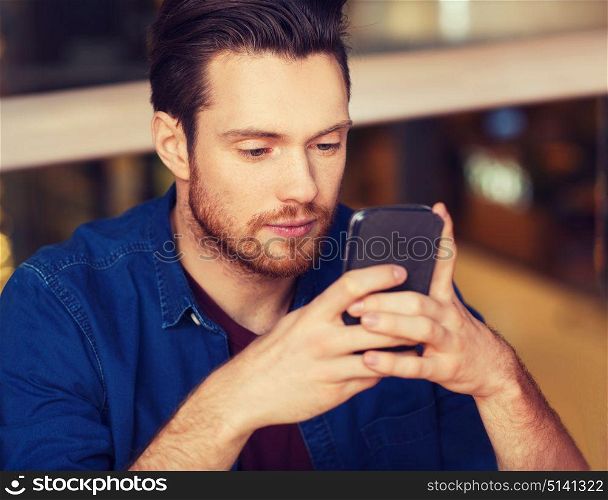 leisure, technology, internet addiction, lifestyle and people concept - man with smartphone reading message at restaurant. man with smartphone reading message at restaurant