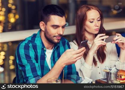 leisure, technology, lifestyle and people concept - couple with smartphones dining at restaurant. couple with smartphones dining at restaurant