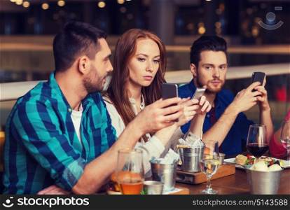leisure, technology, lifestyle and people concept - friends with smartphones dining at restaurant. friends with smartphones dining at restaurant