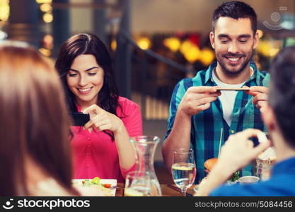 leisure, technology, lifestyle and people concept - happy friends with smartphones taking picture of food at restaurant. happy friends taking picture of food at restaurant. happy friends taking picture of food at restaurant