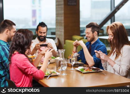 leisure, technology, lifestyle and people concept - happy friends with smartphones taking picture of food at restaurant