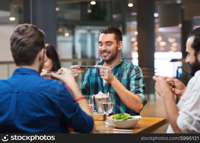 leisure, technology, lifestyle and people concept - happy friends with smartphones taking picture of food at restaurant