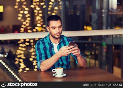 leisure, technology, lifestyle and people concept - man with smartphone and coffee at restaurant. man with smartphone and coffee at restaurant