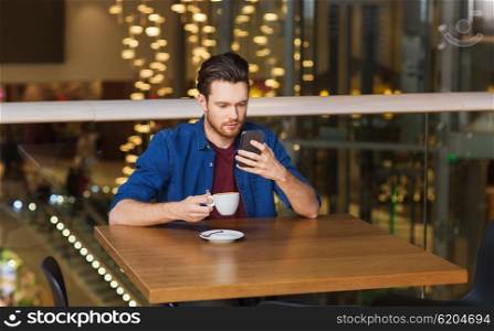 leisure, technology, lifestyle and people concept - man with smartphone and coffee at restaurant