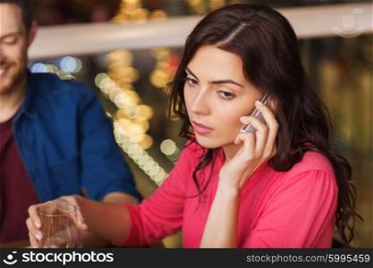 leisure, technology, lifestyle and people concept - woman calling on smartphone and dining at restaurant with friends. woman with smartphone and friends at restaurant