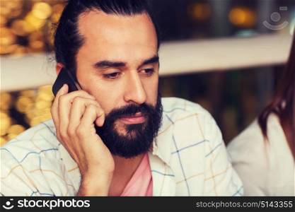 leisure, technology, lifestyle, communication and people concept - sad man calling on smartphone at restaurant. sad man calling on smartphone at restaurant