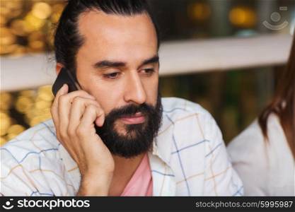 leisure, technology, lifestyle, communication and people concept - sad man calling on smartphone at restaurant