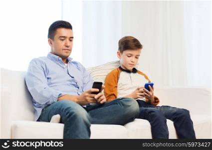 leisure, technology, technology, family and people concept - father and son with smartphones texting message or playing game at home