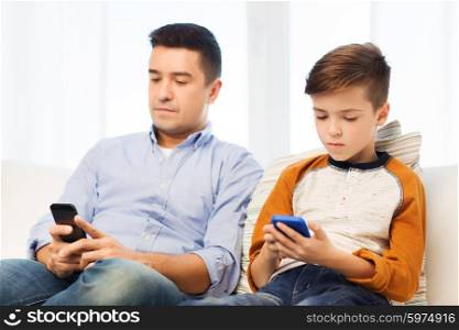 leisure, technology, technology, family and people concept - father and son with smartphones texting message or playing game at home