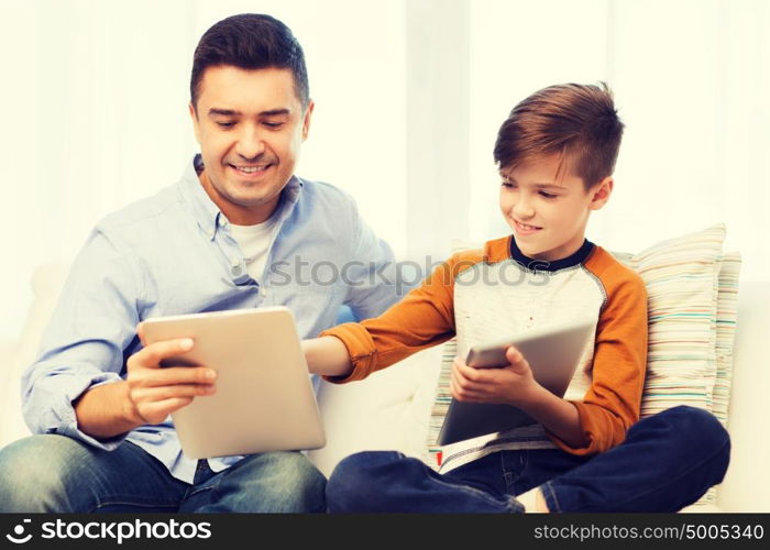 leisure, technology, technology, family and people concept - happy father and son with tablet pc computer networking or playing at home. happy father and son with tablet pc at home