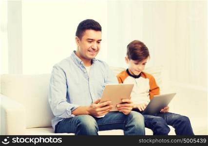 leisure, technology, technology, family and people concept - happy father and son with tablet pc computer networking or playing at home. happy father and son with tablet pc at home