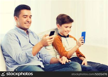 leisure, technology, technology, family and people concept - happy father and son with smartphones texting message or playing game at home. happy father and son with smartphones at home