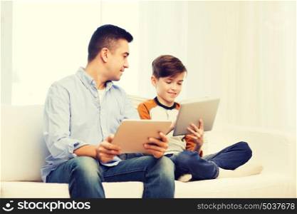 leisure, technology, technology, family and people concept - happy father and son with tablet pc computer networking or playing at home. happy father and son with tablet pc at home