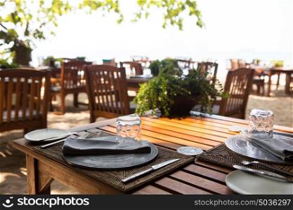 leisure, travel and tourism concept - served table at open-air restaurant on beach. served table at open-air restaurant on beach