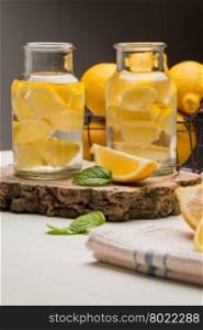 Lemon and lime slices in jars in summer wooden background.