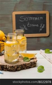 Lemon and lime slices in jars in summer wooden background.