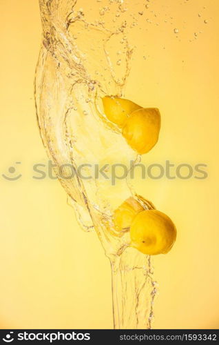 Lemon halves splashing in mid air against yellow background. Splash photography background. Lemon halves splashing in mid air against yellow background