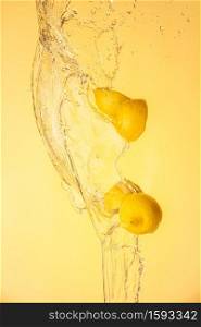 Lemon halves splashing in mid air against yellow background. Splash photography background. Lemon halves splashing in mid air against yellow background