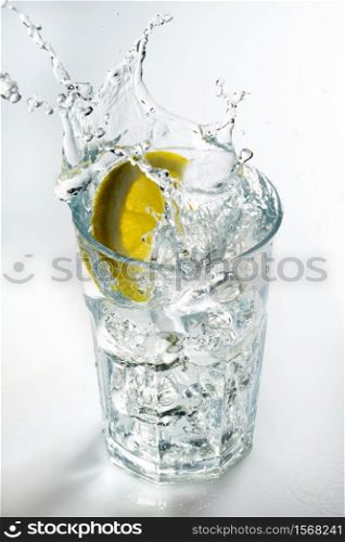 Lemon splashing on a glass against a white background