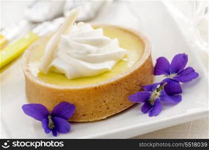 Lemon tart dessert. Fresh gourmet lemon dessert tart with edible violet flowers garnish