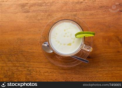 Lemon yogurt fresh milk in a clear glass placed on a brown wooden table with sea water surface background. Top view.