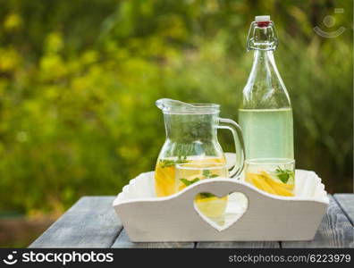 Lemonade drink in the glasses and jug on the white tray. Lemonade in the jug